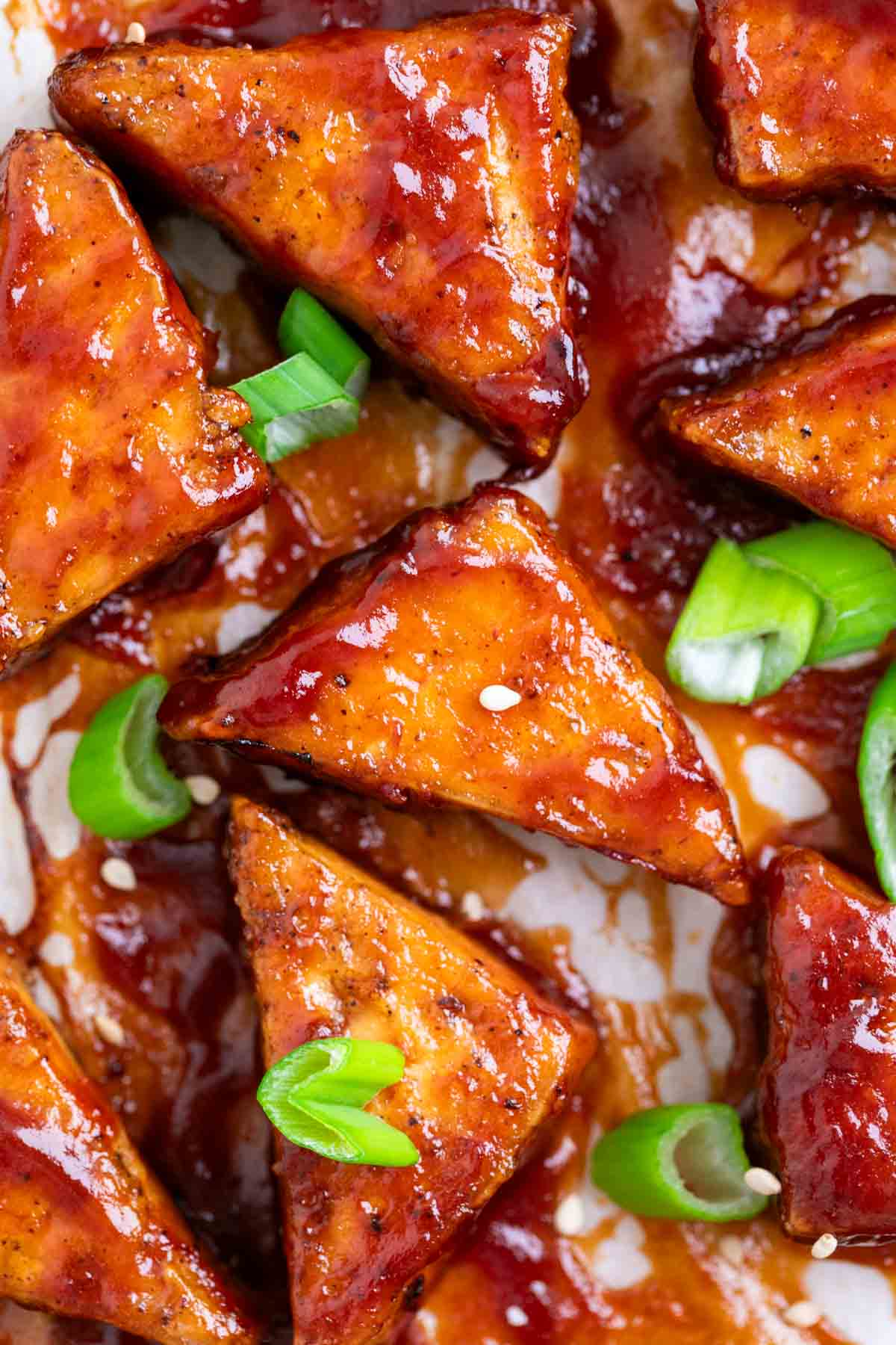 Tofu con salsa barbacoa caramelizada sobre papel de horno con cebolleta