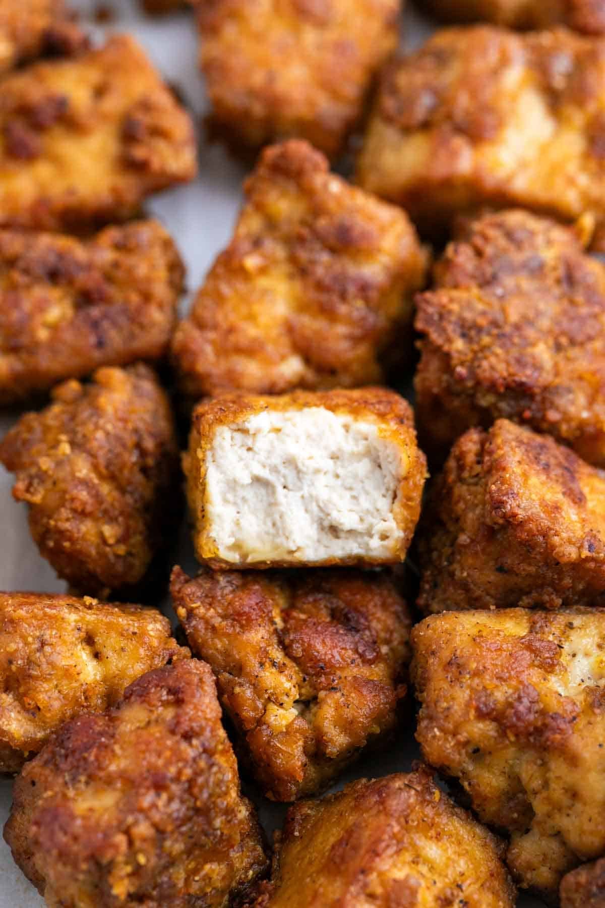 Tofu estilo pollo dorado con un trozo mordido que deja ver el interior