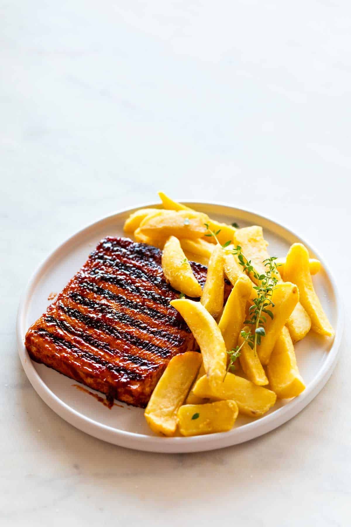 Filetes de tofu con patatas fritas y or&eacute;gano fresco en un plato