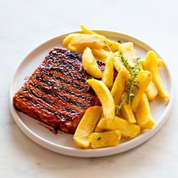 Dos filetes de tofu con marcas de grill servidos con patatas fritas