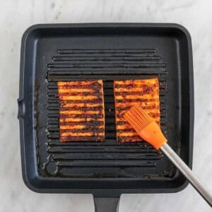 Brocha untando marinado en unos filetes de tofu sobre la parrilla