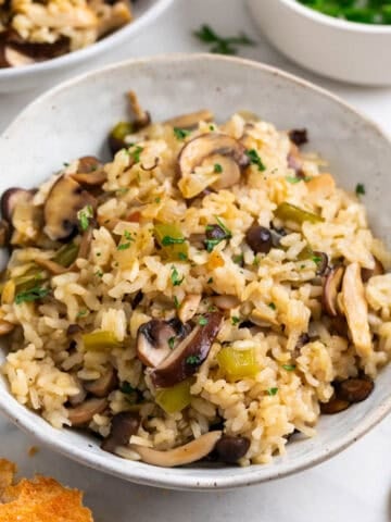Arroz con setas servido en dos platos junto a un trozo de pan y perejil