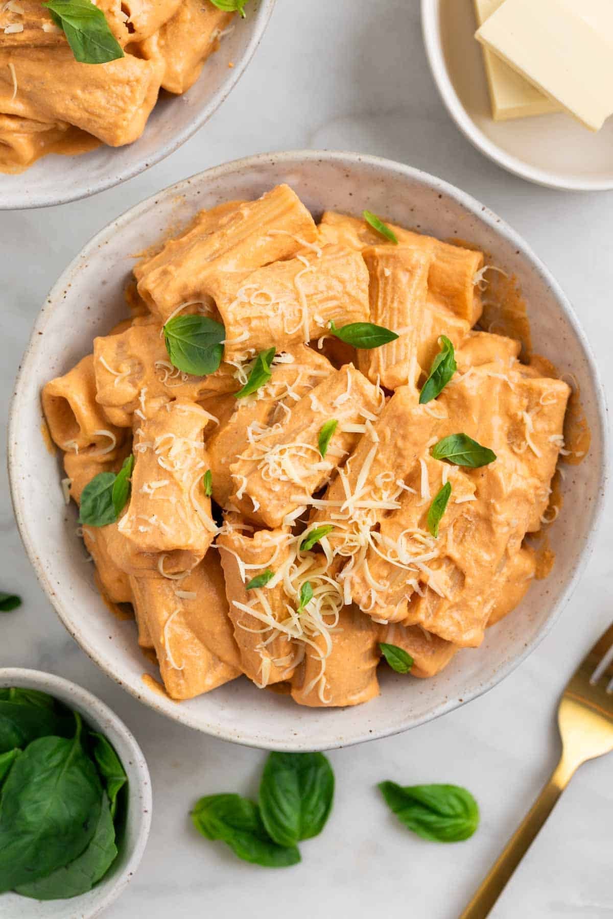 Dos platos de pasta con tofu decorados con albahaca y parmesano vegano