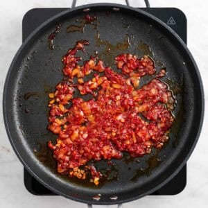 Tomate concentrado y cayena cocinándose con la cebolla y el ajo