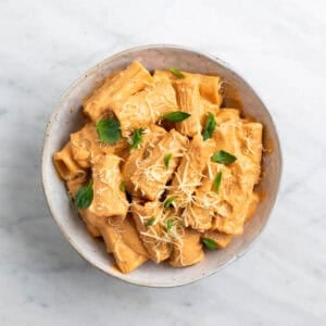 Pasta con tofu servida con albahaca fresca y parmesano vegano