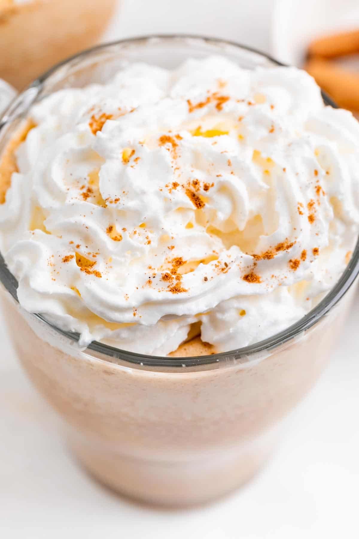Dos tazas de pumpkin spice latte decoradas con nata y rodeadas de ingredientes