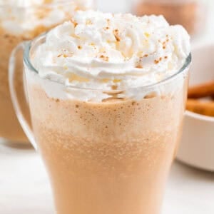 Dos pumpkin spice latte servidos en tazas con puré de calabaza y especias alrededor