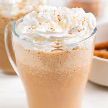 Dos pumpkin spice latte servidos en tazas con puré de calabaza y especias alrededor