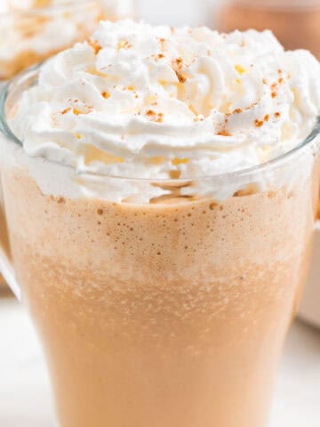 Dos pumpkin spice latte servidos en tazas con puré de calabaza y especias alrededor