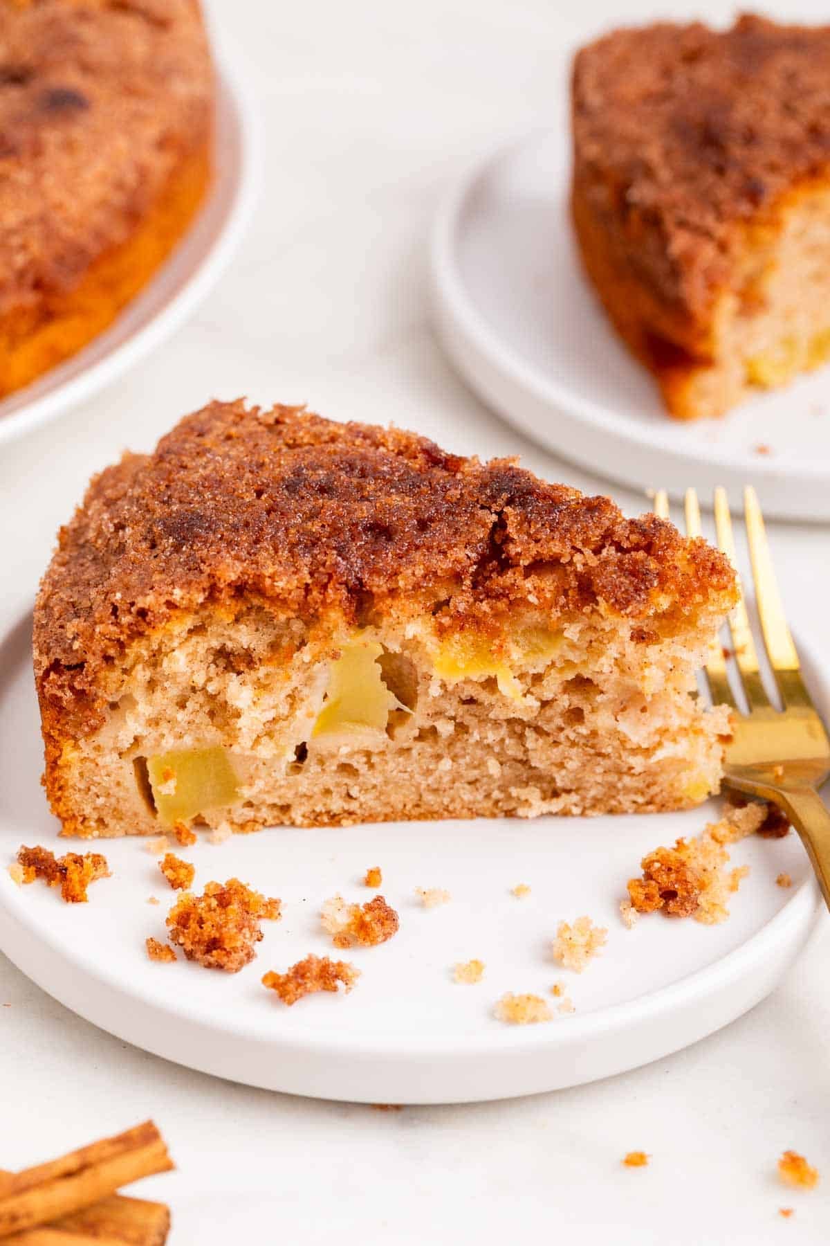 Porci&oacute;n de bizcocho de manzana vegano con ramas de canela y un tenedor