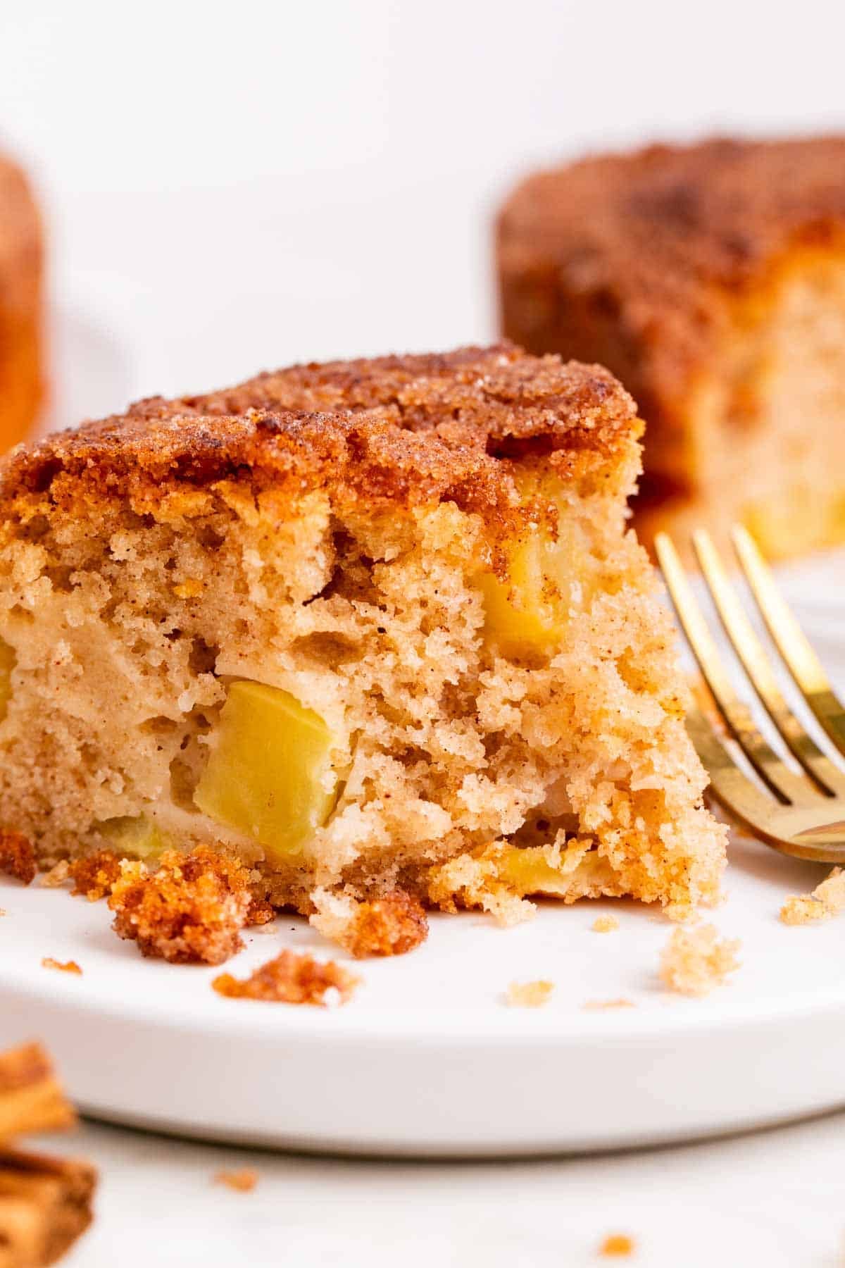 Bizcocho de manzana vegano con una porción servida, canela y un tenedor