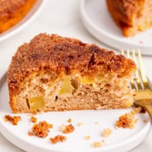 Porción de bizcocho de manzana vegano en un plato con canela y un tenedor