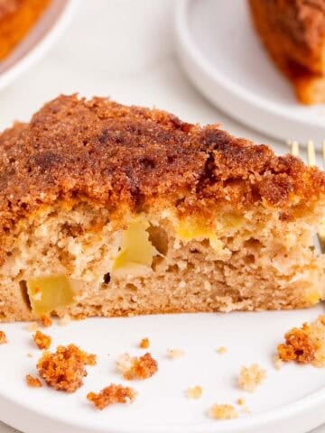 Porción de bizcocho de manzana vegano en un plato con canela y un tenedor