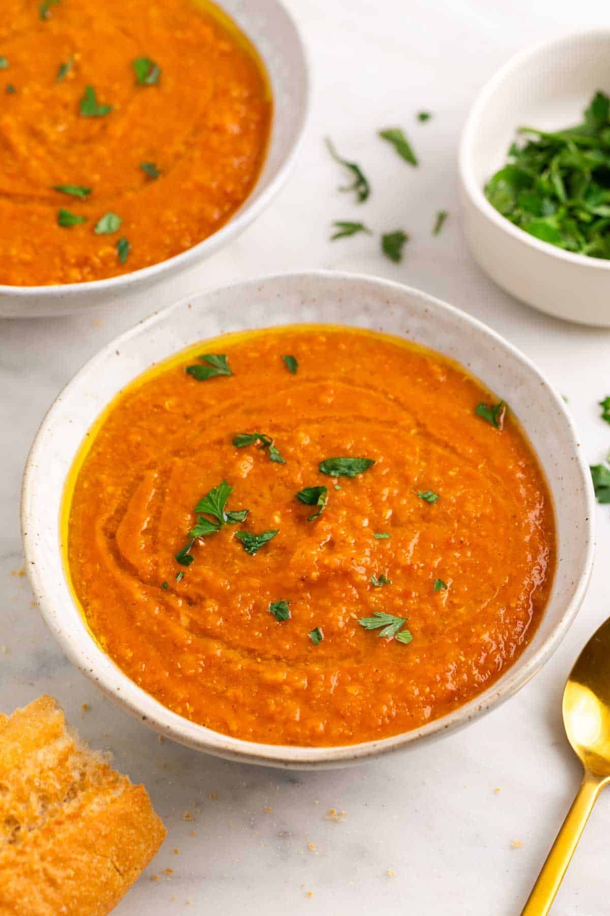 Crema de lentejas rojas servida en dos platos con perejil y aceite
