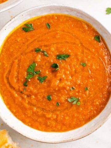Crema de lentejas rojas decorada con perejil y un chorrito de aceite