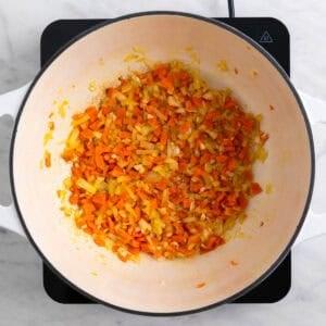 Ajo, cebolla y zanahoria cocinándose en una olla