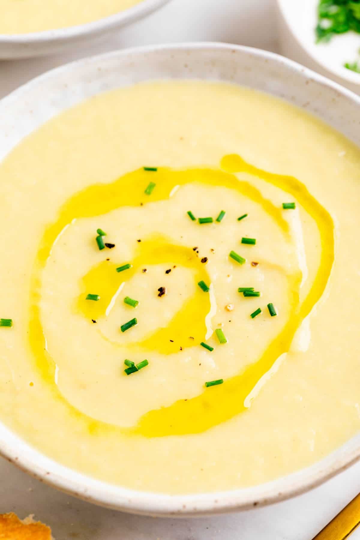 Crema de puerros servida en dos platos con cebollino y aceite de oliva