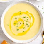 Crema de puerros en dos platos con cebollino, aceite, pan y una cuchara