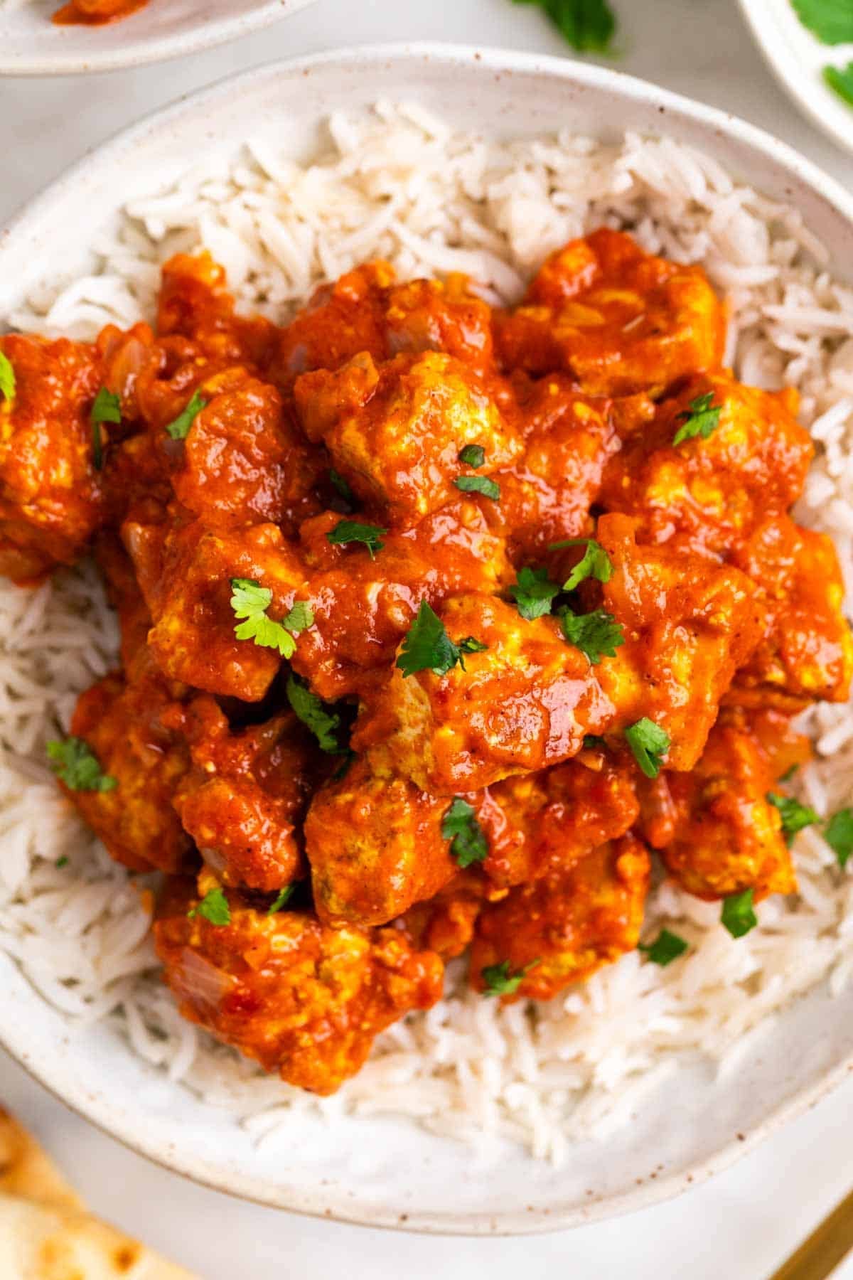 Dos boles de arroz con tofu tikka masala decorado con perejil picado
