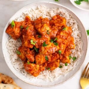 Dos boles de tofu tikka masala con arroz, perejil picado y pan naan